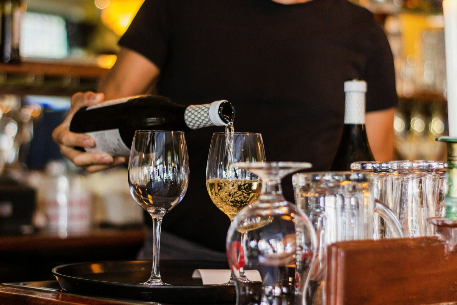 Vin turnat în pahare, lângă un decantor